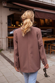 Blazer ample à épaulettes porté par une femme, vue de dos, queue de cheval, jean clair