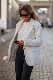 Blazer effet laine à épaulettes porté par une femme, vue de trois-quarts, lunettes de soleil, téléphone, jean noir, pavés