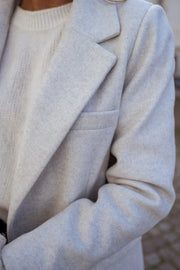 Blazer effet laine à épaulettes porté par une femme, gros plan du revers et de la poche