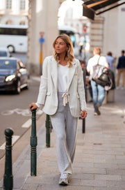 Blazer effet laine à épaulettes porté par une femme, en marchant, rue, pantalon clair, bornes