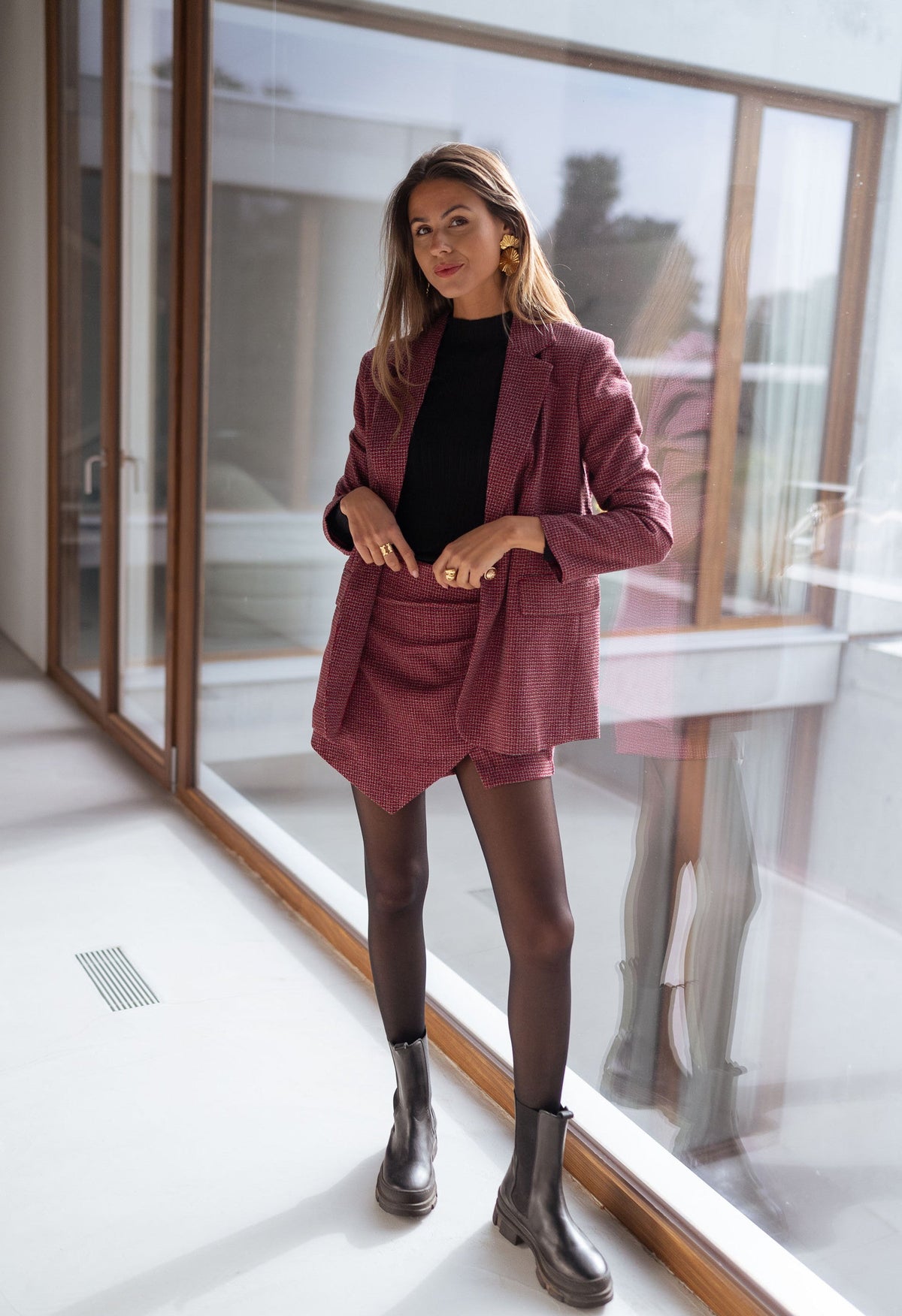 Veste à carreaux doublée portée par une femme, vue de face, baie vitrée, bottes noires