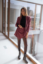 Veste à carreaux doublée portée par une femme, vue de face, baie vitrée, jupe assortie