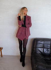 Veste à carreaux doublée portée par une femme, vue de face, fauteuil en cuir noir, bottines noires