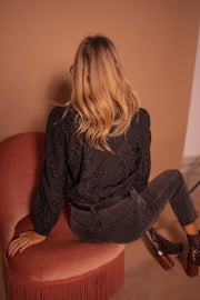 Blouse à poignets élastiques portée par une femme, vue de dos, fauteuil rose, cheveux longs