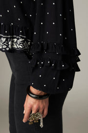 Blouse courte noire à pois — détail ourlet et poignet brodés