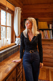 Blouse courte en dentelle portée par une femme, silhouette entière, fenêtre, jean, ceinture