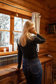 Blouse courte en dentelle portée par une femme, vue de dos, fenêtre, cheveux longs