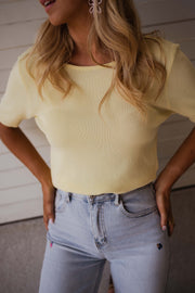 Blouse dos ouvert à nouer jaune portée par une femme, vue rapprochée, t-shirt jaune, jean clair