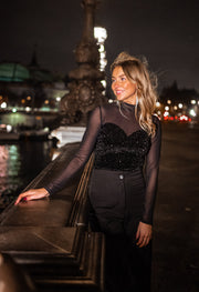 Blouse en velours à paillettes portée par une femme, vue de trois-quarts, debout, rambarde, de nuit