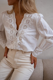 Blouse brodée aux poignets portée par une femme, vue rapprochée, col V, dentelle