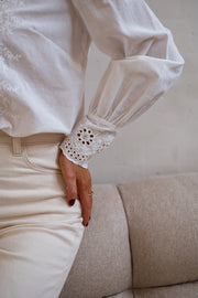 Blouse brodée aux poignets portée par une femme, gros plan du poignet brodé