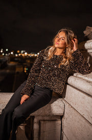 Blouse courte en velours portée par une femme, assise, sur la rambarde, de nuit