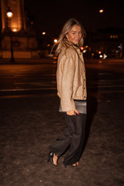 Bomber entièrement pailleté porté par une femme, silhouette entière, de nuit, pantalon large, sac