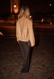 Bomber entièrement pailleté porté par une femme, vue de dos, de nuit, pantalon noir, rue
