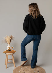 Bombers oversize en velours côtelé porté par une femme, vue de dos, jean flare, tabouret