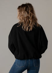 Bombers en velours côtelé oversize porté par une femme, vue de dos, veste noire, jean