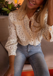 Chemise fluide à fleurs portée par une femme, vue rapprochée, volants au col, sourire