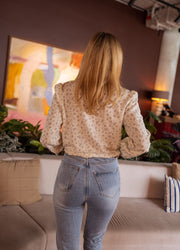 Chemise fluide à fleurs portée par une femme, vue de dos, jean clair, canapé