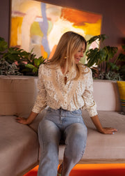 Chemise fluide à fleurs portée par une femme, assise, sur un canapé, de face
