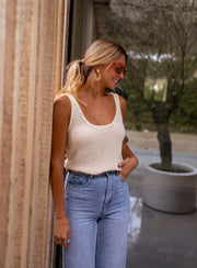 Top crochet ajouré à manches courtes porté par une femme, silhouette entière, mur en bois, queue de cheval