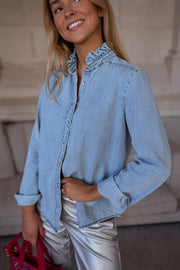 Chemise en jean à volant portée par une femme, vue rapprochée, sourire, col