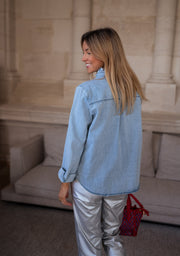 Chemise en jean à volant portée par une femme, vue de dos, pantalon argenté