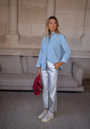 Chemise en jean à volant portée par une femme, silhouette entière, pantalon argenté, baskets