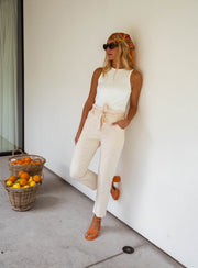 Top moulant col rond blanc porté par une femme, vue de trois-quarts, mur blanc, panier