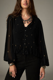 Blouse noire à pois brodés — gros plan du col en V et liens