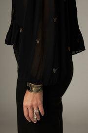 Blouse noire à pois brodés — détail du poignet à volant