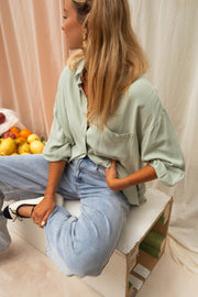 Chemise en coton fluide portée par une femme, assise, jean, rideaux