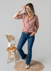 Blouse vichy à petits cœurs portée par une femme, vue de trois-quarts, main sur la hanche