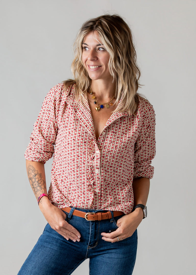Blouse vichy à petits cœurs portée par une femme, vue rapprochée, mains dans les poches, jean