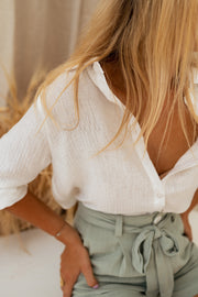 Chemise à col et boutons portée par une femme, vue rapprochée, short vert sauge, nœud