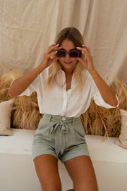 Chemise à col et boutons portée par une femme, vue rapprochée, lunettes, mains
