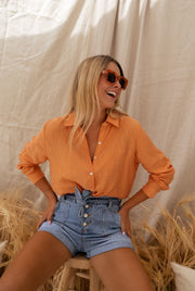 Chemise fluide à col classique portée par une femme, silhouette entière, botte de paille, short en jean