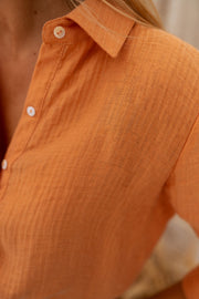 Chemise fluide à col classique portée par une femme, vue rapprochée, tissu froissé, col