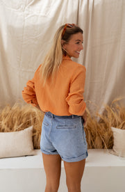 Chemise fluide à col classique portée par une femme, vue de dos, short en jean, banquette