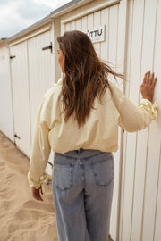 Chemise à poche fleurie portée par une femme, vue de dos, cabine de plage, cheveux longs