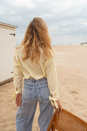 Chemise à poche fleurie portée par une femme, vue de dos, plage, jean large