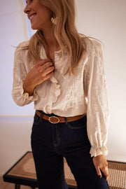 Chemise brodée à volants portée par une femme, vue rapprochée, main sur le col