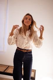 Chemise brodée à volants portée par une femme, vue rapprochée, mains près du col