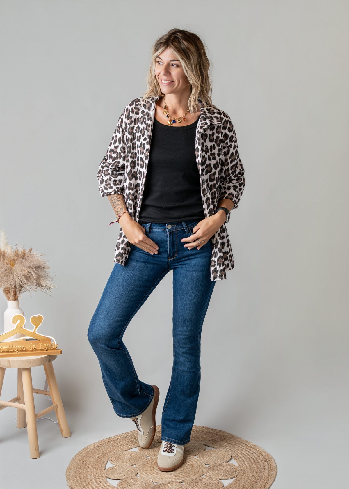 Chemise léopard en gaze portée par une femme, silhouette entière, jean évasé, fond gris