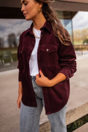 Chemise en velours ample bordeaux portée par une femme, vue rapprochée, cheveux longs, jean