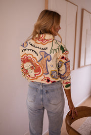 Chemise en coton à motifs portée par une femme, vue de dos, imprimé coloré, chaise en bois