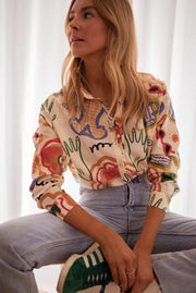 Chemise en coton à motifs portée par une femme, assise, cheveux longs, baskets vertes