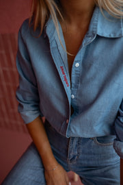 Chemise en denim fluide portée par une femme, gros plan du col et des boutons