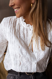 Blouse brodée en dentelle portée par une femme, vue rapprochée, col volanté, sourire