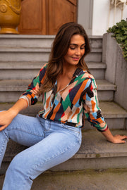 Chemise fluide à motifs multicolore portée par une femme, assise, marches, jean