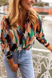 Chemise fluide à motifs multicolore portée par une femme, vue rapprochée, motifs géométriques, jean